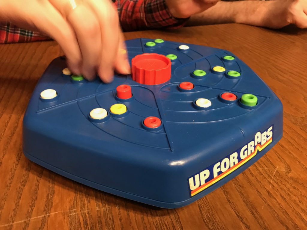 A hand reaching for a peg mid-play