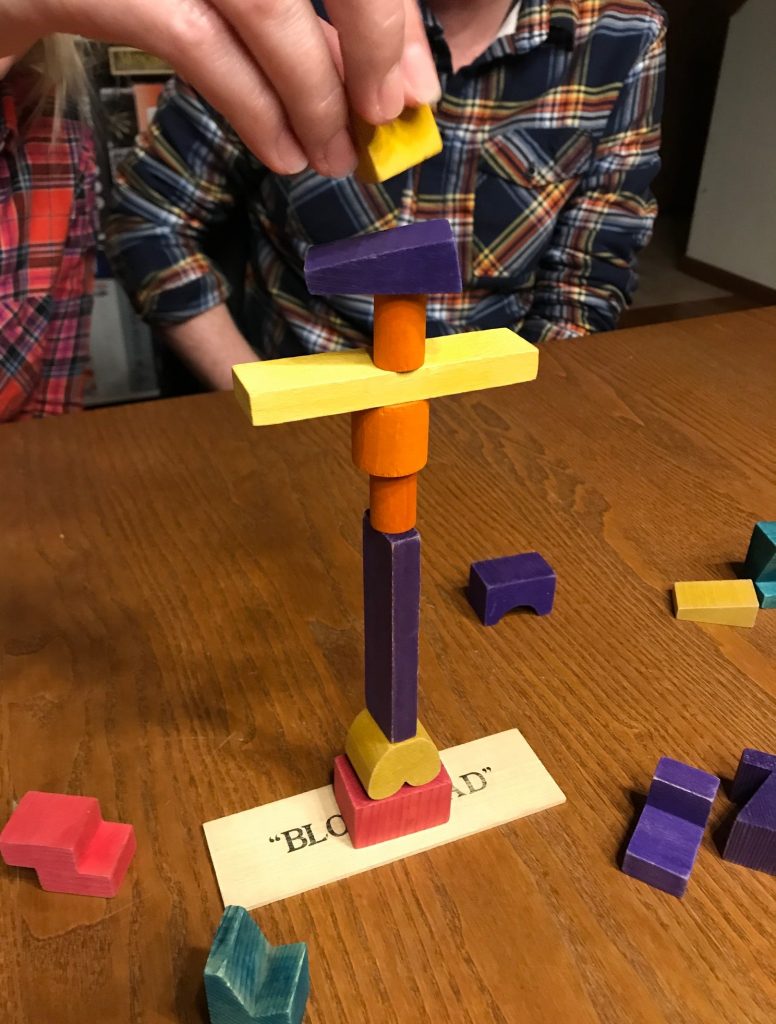 An action shot showing a hand placing a block on a structure that is already 9 blocks tall