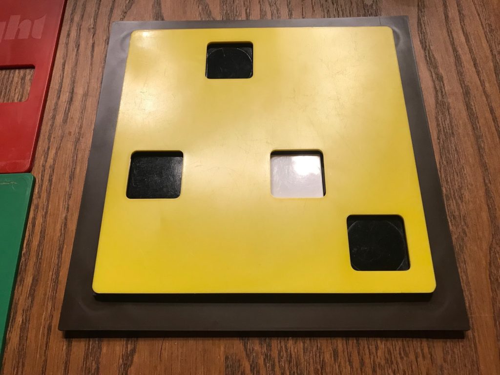 The board with a yellow KEY PLATE on it showing three black TABLETS and one white TABLET