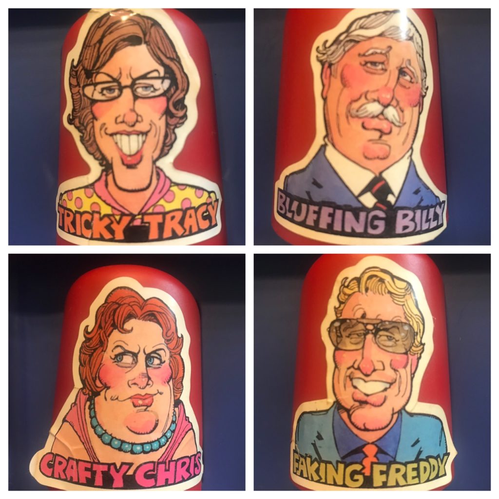 The four dice shakers have cartoonish faces and names via sticker